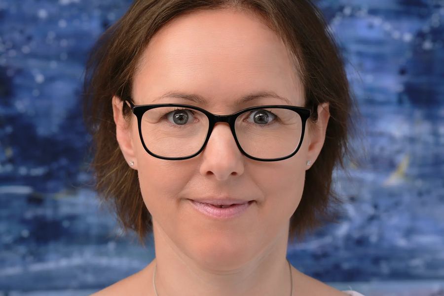Business-Portrait mit Brille vor blauem Hintergrund